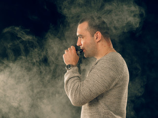 smoking man in e-cigarette smoke on black background