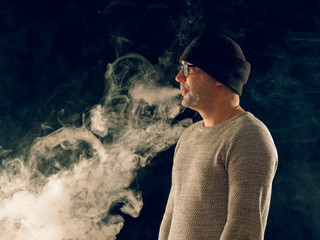 Fototapeta na wymiar smoking man in e-cigarette smoke on black background