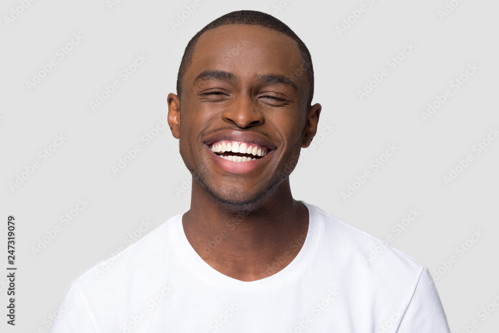 Wall mural Cheerful happy african millennial man laughing looking at camera isolated on studio blank background, funny young black guy with healthy teeth beaming orthodontic white wide smile head shot portrait