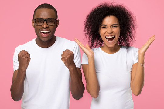 Overjoyed excited african american family couple winners celebrate win enjoy victory rejoice success, happy ecstatic euphoric black man and woman screaming with joy isolated on pink studio background