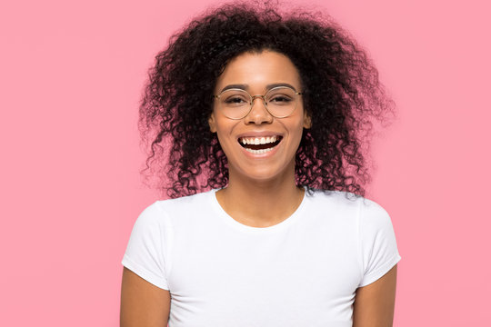 Cheerful funny young african american girl wearing optical glasses laughing isolated on pink blank studio background, happy black woman student in eyeglasses having fun looking at camera, portrait