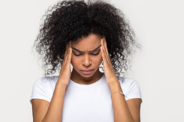 Upset stressed black woman massaging temples feeling pain terrible migraine, sad tired sick african american girl suffering from strong headache concept isolated on grey white blank studio background