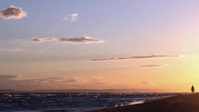 Promeneur marche le long de la mer M&eacute;dit&eacute;rrann&eacute;e sur la plage de sable fin au coucher du soleil	