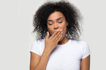 Fototapeta na wymiar Tired funny drowsy african american woman yawning isolated on white grey studio background, sleepy inattentive deprived black female feeling somnolent lazy bored gaping suffering from lack of sleep