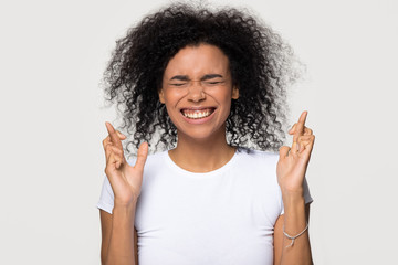Funny superstitious black woman crossing fingers wishing for good luck, stressed hopeful african...