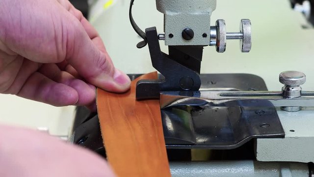 man using a machine to frame the edge of a leather piece of material. Close up view. Craft and handmade concept