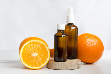 Cosmetics bottles and fresh oranges,wooden board against white wall.Concept of spa treatments