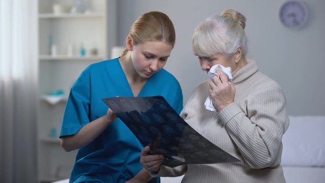 Medical worker explaining old woman x-ray examination results, diagnosis, health