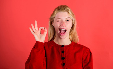 Girl wink happy face while show ok gesture over red background. Woman satisfied with everything. Everything is ok or fine. Alright concept. Alright gesture body language. Things gonna be alright