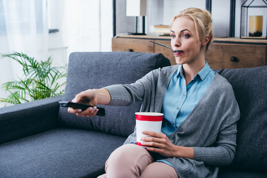 Woman Eating Ice Cream While Siitng On Couch And Wathicng Tv At Home Alone