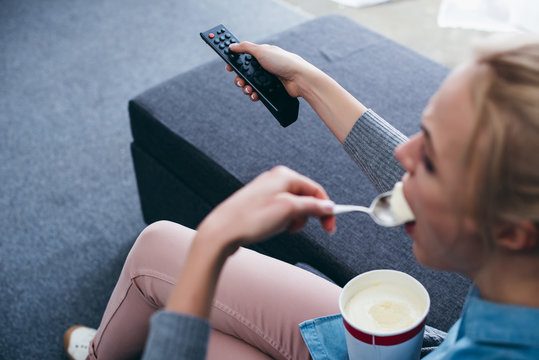 Cropped View Of Woman Sitting On Couch And Eating Ice Cream While Watching Tv