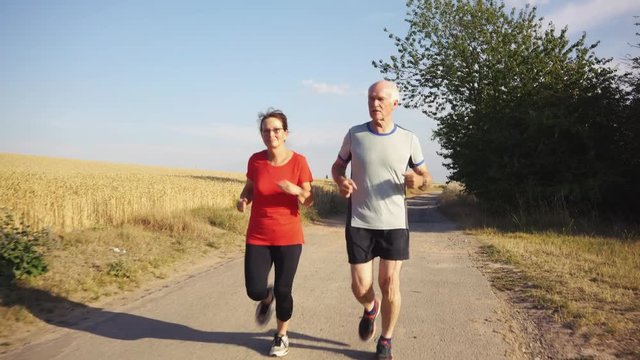 Senior woman and man running or jogging on a field to remain fit and healthy