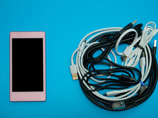 pink smartphone with pile of cables on blue background. phone service fix concept
