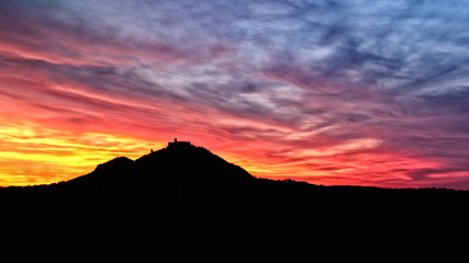 Fototapeta premium sunset and colorful red yellow clouds with a silhouette of a castle on a hill