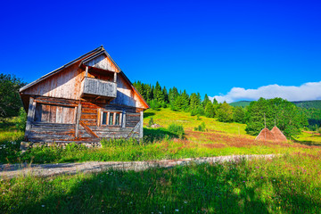 Beautiful countryside landscape with forested hills and haystacks on a grassy rural field in mountains