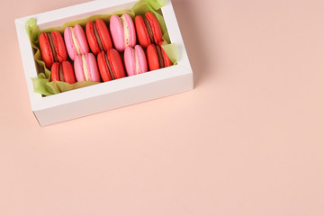 Tasty sweet cookies macaron, macaroon in a white gift box on a pink background, red and pink macarons. Copy space
