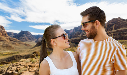 travel, tourism and people concept - happy couple in sunglasses outdoors in summer over grand canyon national park background