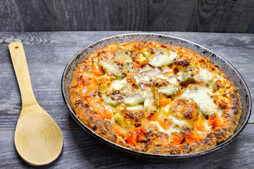 Vegetable and cheese pie close up in vintage pan with wooden spoon on grey wooden rustic background