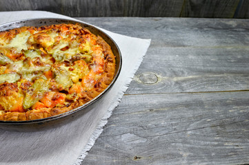 Vegetable and cheese pie in vintage pan on white linen napkin on wooden rustic background