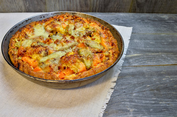 Vegetable and cheese pie in vintage pan on white linen napkin on wooden rustic background