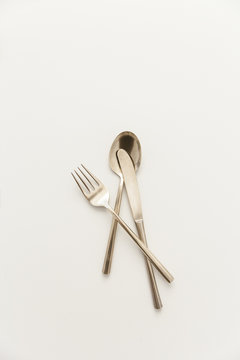 A bunch of brass cutlery on a grey surface.