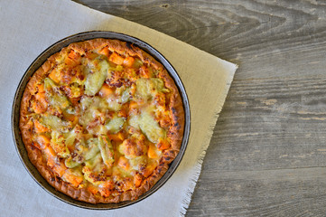 Vegetable and cheese pie in vintage pan on white linen napkin on wooden rustic background