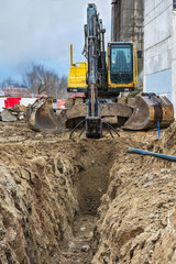 Excavator with a drill making a narrow ditch to put gas pipes