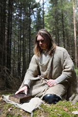 A man in a cassock spends a ritual in a dark forest