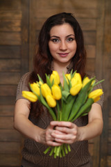 Girl with a bouquet of yellow tulips. Girl with a gift of flowers in a vase. A gift for girls on a female holiday with yellow tulips on the floor.