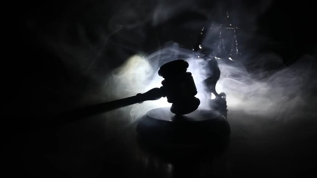 Law theme, mallet of the judge on wooden desk with Lady Justice Statue. Law gavel on dark foggy background with light. Selective focus