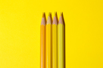 Three yellow pencils on a bright yellow background with a hard shadow. stationery. top view. space...