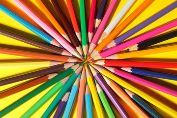 Composition with colored pencils on a bright yellow background. close-up. top view