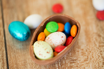 easter, junk-food, confectionery and unhealthy eating concept - close up of chocolate egg and candy drops on table