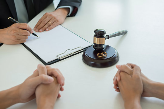 Judge gavel with Justice lawyers deciding, consultation on marriage divorce between married couple and signing divorce documents on table. Concepts of Law and Legal sevices.