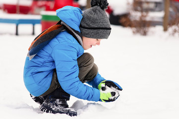 funny boy playing snowballs in the winter outside