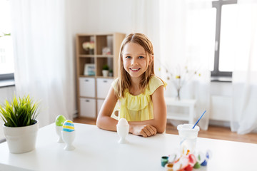 easter, holidays and people concept - happy girl with eggs and colors at home