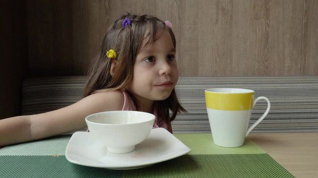 Beautiful cute little child, baby gerl, drink tea. Kid having breakfast.
