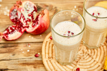 Smoothie with oat or oatmeal, banana and pomegranate on wooden rustic background.