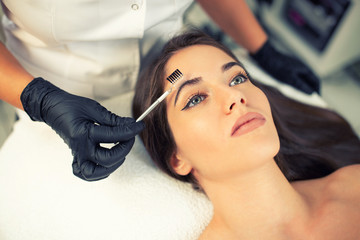 Naklejka premium Certified beautician preparing her client eyebrows