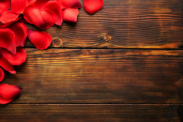 Romantic happy valentines day greeting card, wedding invitation concept. Frame made of red, scarlet, crimson rose petals on dark wooden floor. Close up, top view, copy space, mock up, background.