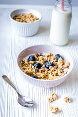 Homemade fitness granola with yoghurt and berries on white kitchen background