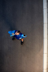 Top view of young bearded runner standing on the street in sportswear and drinking water. Around arm smart phone case.