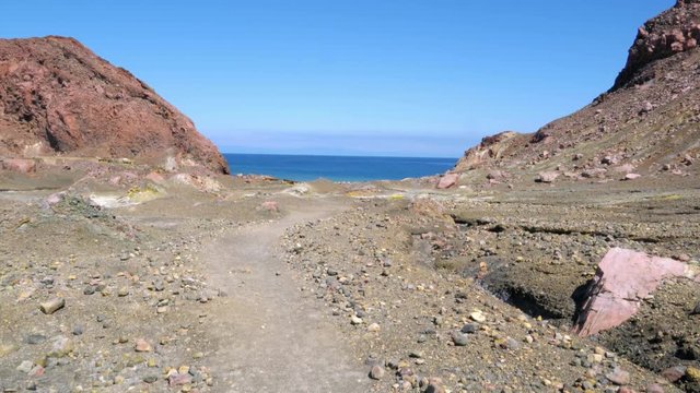 Handheld shot of fumaroles on coast of White Island in New Zealand. Steam and gasses emitting from ground rich in iron and sulphur