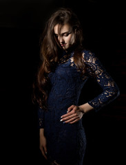 Naklejka premium Sensual attractive young woman in a lace dress poses on a dark background