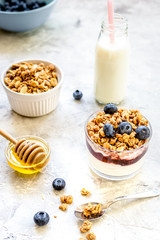 Morning granola in glass with yogurt, honey and milk on white desk