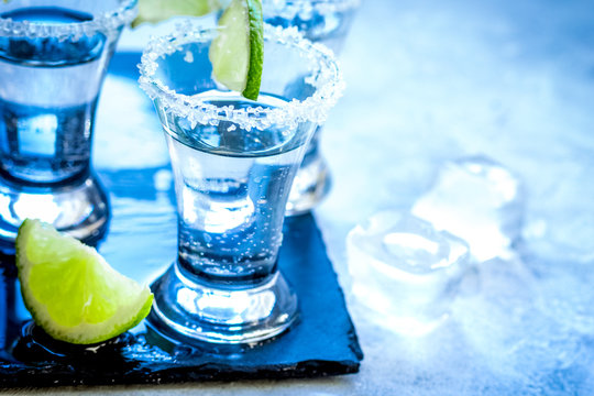 Silver tequila shots with lime and salt on gray stone background