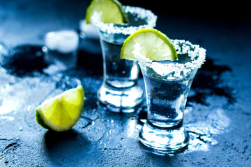 Tequila shot with salt and ice on dark background