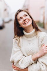 Portrait of young tender redhead young girl with healthy freckled skin wearing knitted scarf looking at camera with serious,pensive expression. Caucasian teen model with ginger hair posing outdoors