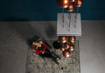 Fashion full length portrait of stylish model in trendy apparel. Woman looks at her reflection in the mirrored ceiling