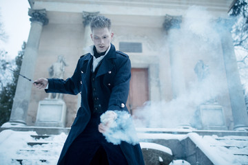 Black magician makes a spell with the help of magic wand and smoke.